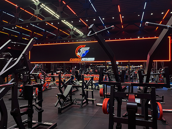 Sala pesi Carmafitness con macchinari e insegna luminosa